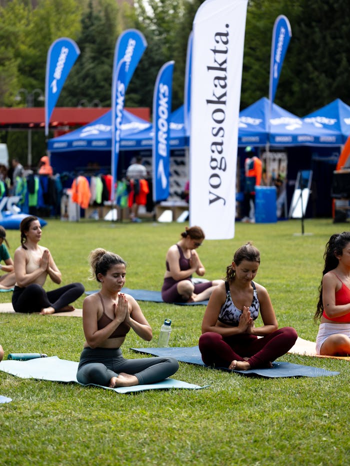People participating in a yoga class outdoors with yoga mats during a community event.