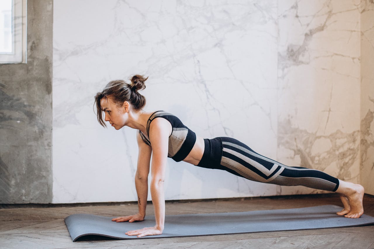 A woman performing a plank pose on a yoga mat indoors, showcasing strength and focus.
