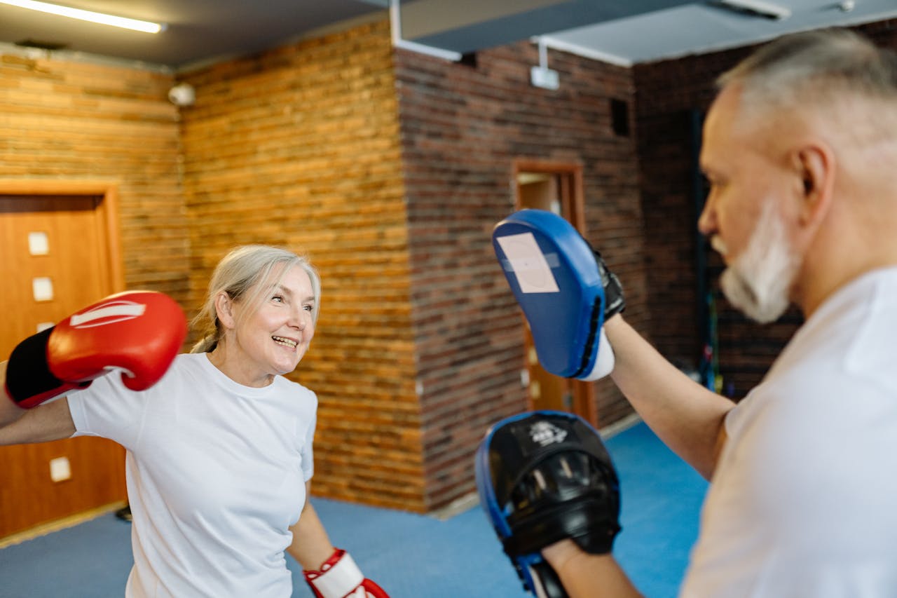 Senior couple practicing boxing indoors for fitness and fun. Emphasizing healthy senior lifestyle.